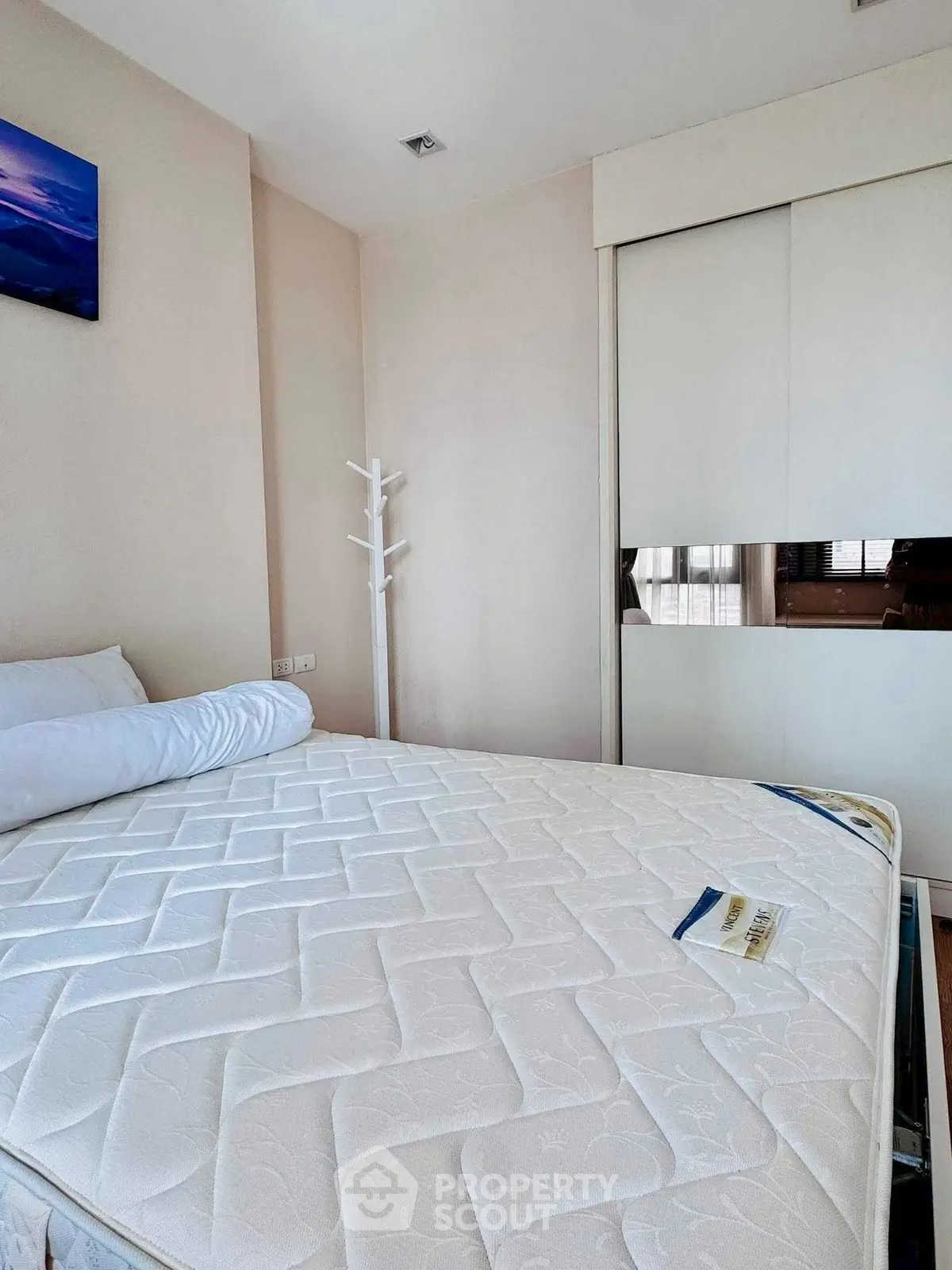 Spacious bedroom with modern decor and ample natural light, featuring a comfortable bed and sleek wardrobe.