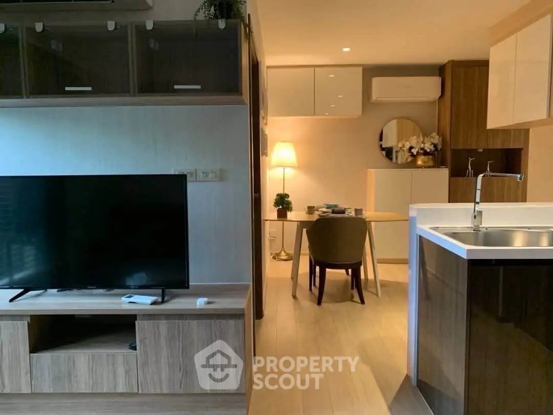 Modern open-plan living room with stylish kitchen and cozy dining area, featuring sleek furniture and warm lighting.