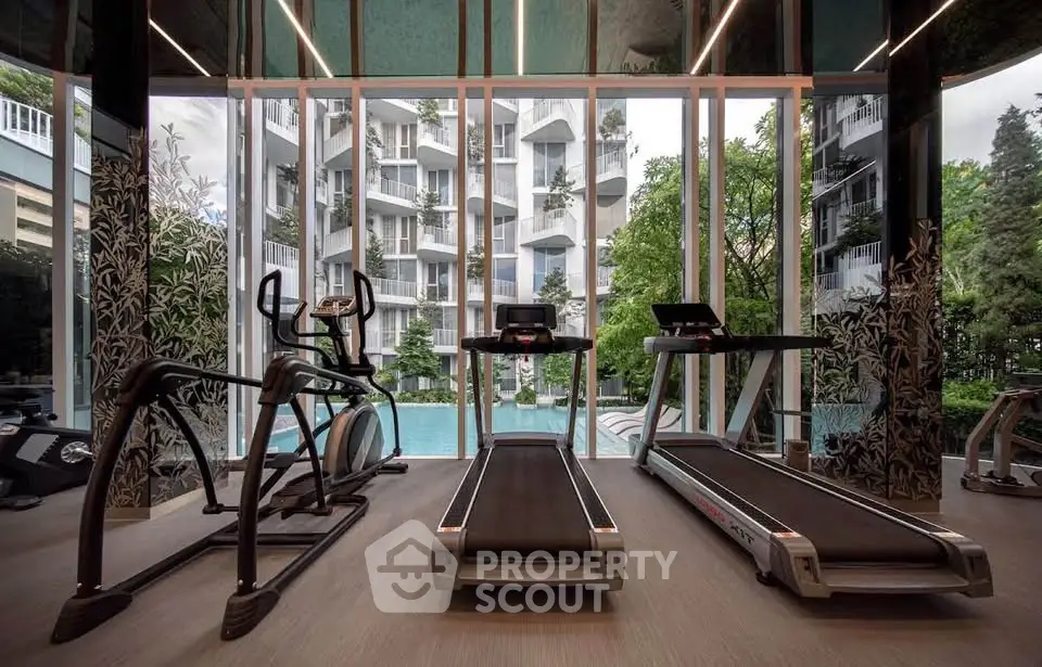 Luxurious gym with modern equipment and stunning pool view in upscale residential building.