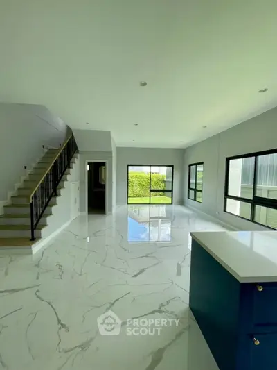 Spacious modern living room with marble flooring and large windows for natural light.