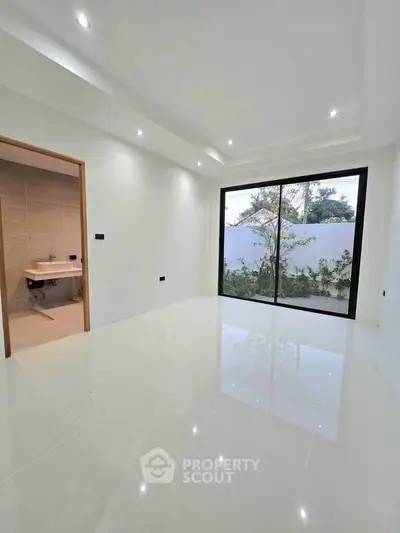 Modern minimalist room with large sliding glass doors and adjacent bathroom, perfect for natural light lovers.