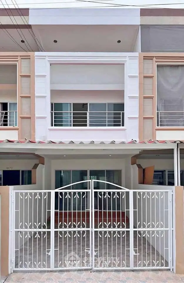 Modern townhouse exterior with gated entrance and balcony, showcasing contemporary design and style.
