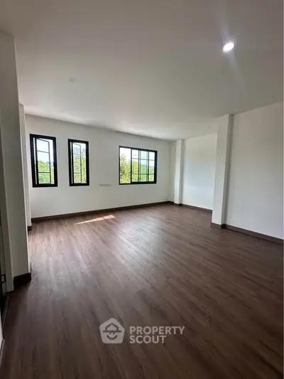 Spacious empty room with large windows and wooden flooring