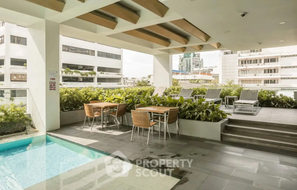 Luxurious rooftop pool area with modern seating and lush greenery in urban setting.