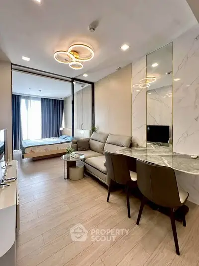Modern open-plan living room with stylish decor and adjacent bedroom in a contemporary apartment.
