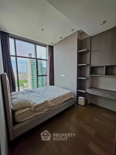 Modern bedroom with large window offering city view, featuring built-in shelves and sleek design.