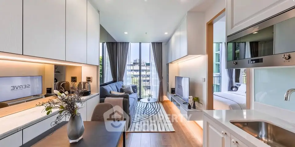 Modern open-plan living room with sleek kitchen and cozy bedroom view, featuring stylish decor and natural light.