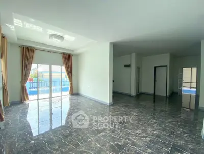 Spacious living room with marble flooring and large windows for natural light.