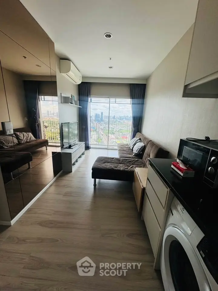 Modern living room with city view, featuring sleek furniture and built-in appliances.