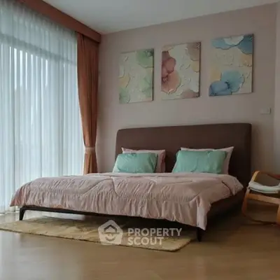 Spacious bedroom with elegant decor and large windows for natural light.