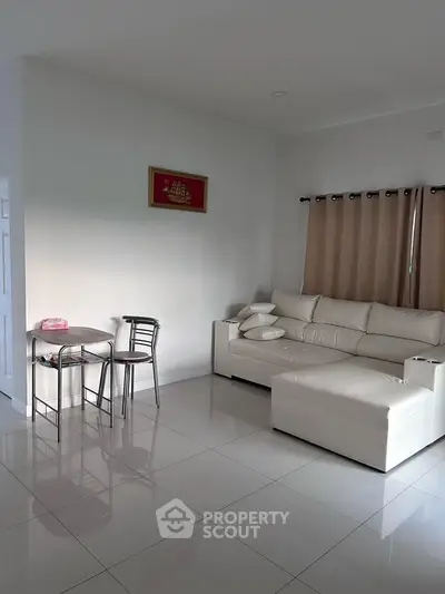 Modern living room with white leather sofa and small dining set, perfect for cozy gatherings.