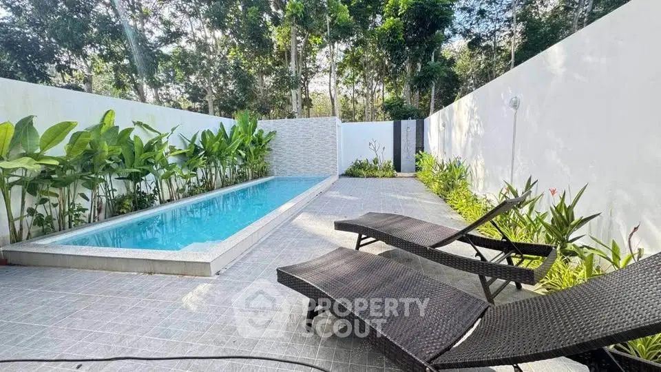 Luxurious private pool area with lush greenery and modern lounge chairs, perfect for relaxation and entertainment.