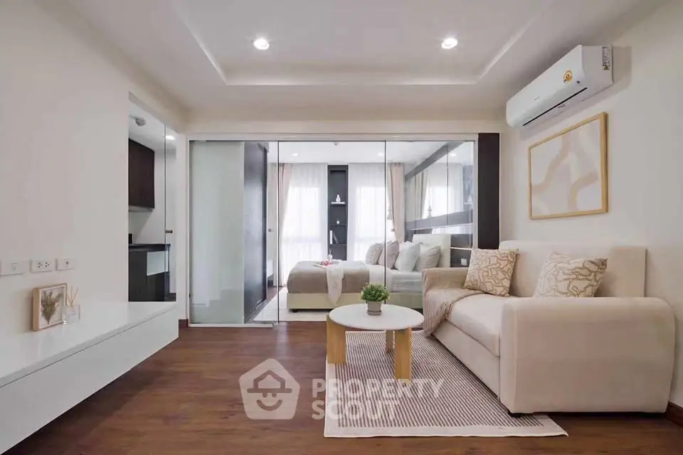 Modern living room with elegant decor and glass partition leading to bedroom.