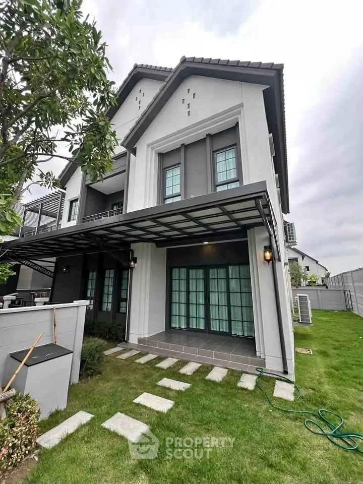 Modern two-story house with landscaped garden and spacious patio, ideal for family living.