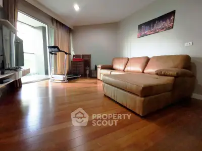 Spacious living room with hardwood floors, cozy leather sofa, and balcony access in modern apartment.