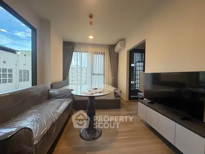 Modern living room with large window, stylish furniture, and natural light in urban apartment.