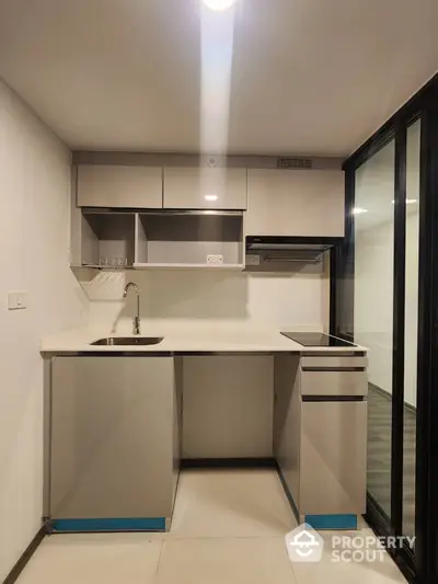 Modern compact kitchen with sleek cabinetry and built-in appliances in a stylish apartment.