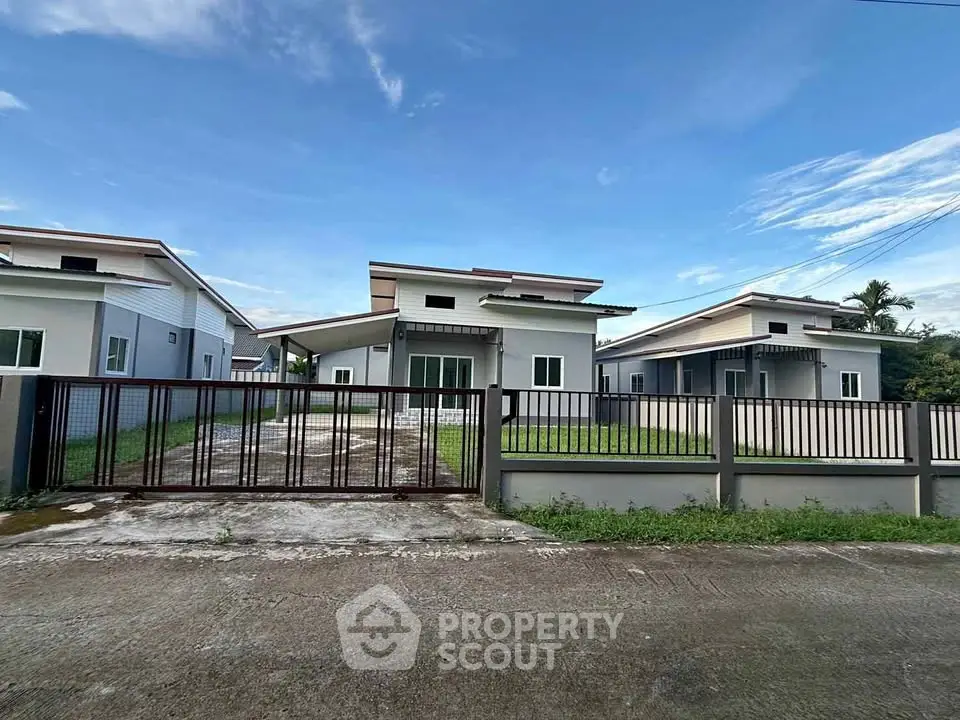 Modern single-story house with spacious driveway and gated entrance in a serene neighborhood.