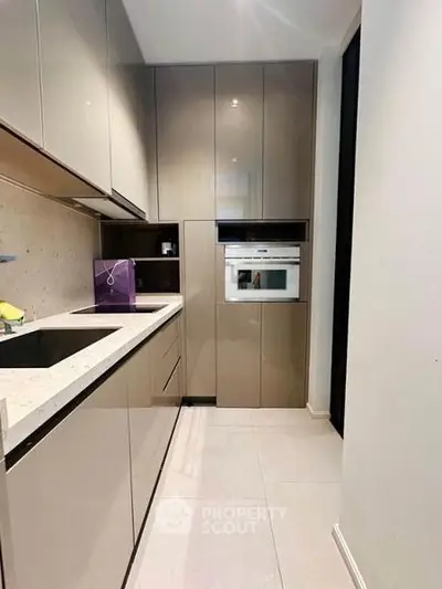 Modern kitchen with sleek cabinetry and built-in oven in a stylish apartment.