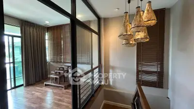 Modern interior with stylish lighting and wooden flooring, featuring a cozy dining area and large windows.