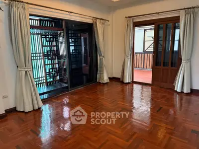 Spacious living room with polished wooden floors and large windows for natural light.