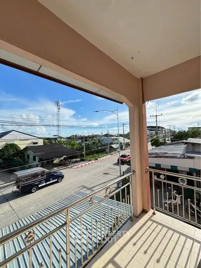 Charming balcony view overlooking a vibrant street with clear blue skies, perfect for urban living.
