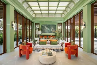Luxurious living room with vibrant decor and expansive glass doors opening to lush greenery.