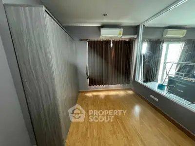 Spacious bedroom with wooden flooring and large window for natural light.