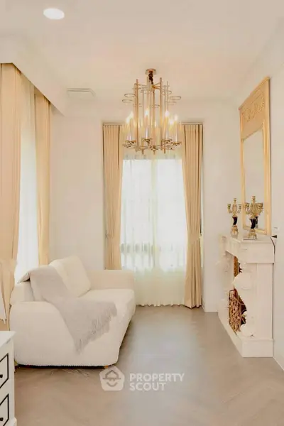 Elegant living room with chandelier and classic fireplace, featuring neutral tones and luxurious decor.