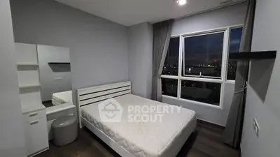 Modern bedroom with city view, featuring sleek furniture and large window for natural light.