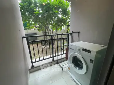 Charming balcony with washing machine and garden view, perfect for urban living convenience.