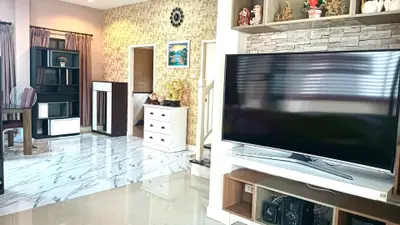 Spacious living room with modern decor and large TV, featuring elegant flooring and stylish shelving.