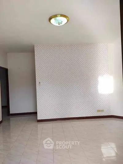 Spacious empty room with tiled flooring and patterned wallpaper, perfect for customization.