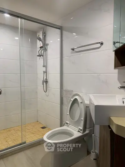 Modern bathroom with glass shower and sleek fixtures in contemporary home.