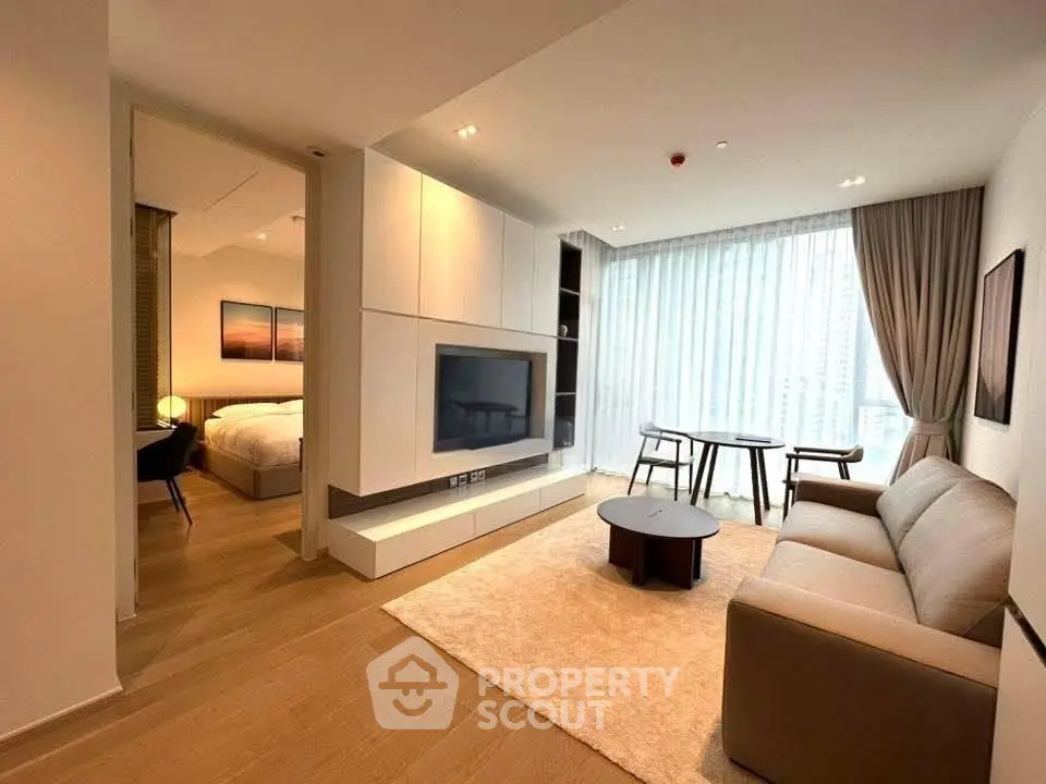 Modern living room with cozy sofa, large TV, and dining area in open-plan apartment.