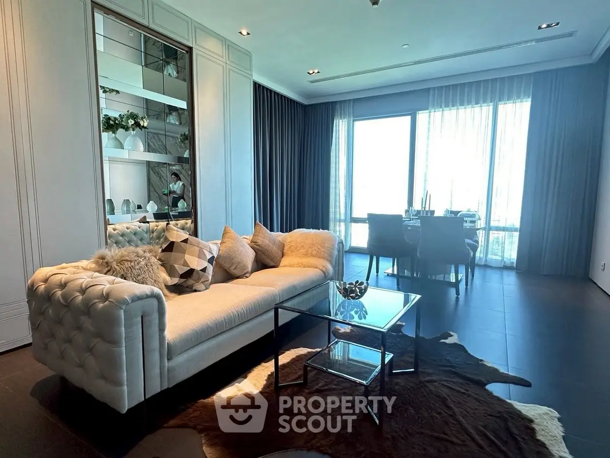 Luxurious living room with elegant sofa and dining area, featuring floor-to-ceiling windows.