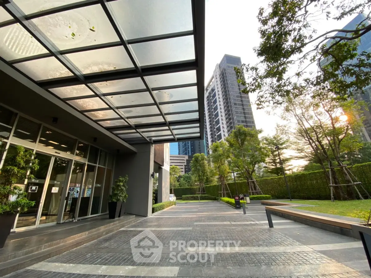 Modern building entrance with glass canopy and landscaped surroundings