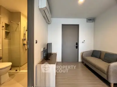 Modern apartment living room with cozy sofa and sleek TV unit, adjacent to a stylish bathroom.