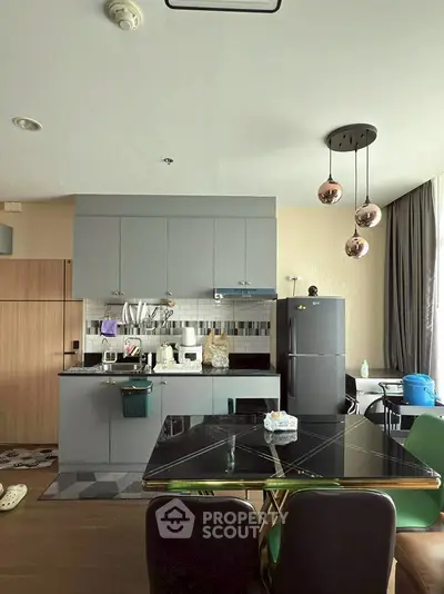 Modern kitchen with sleek cabinetry and dining area in stylish apartment.