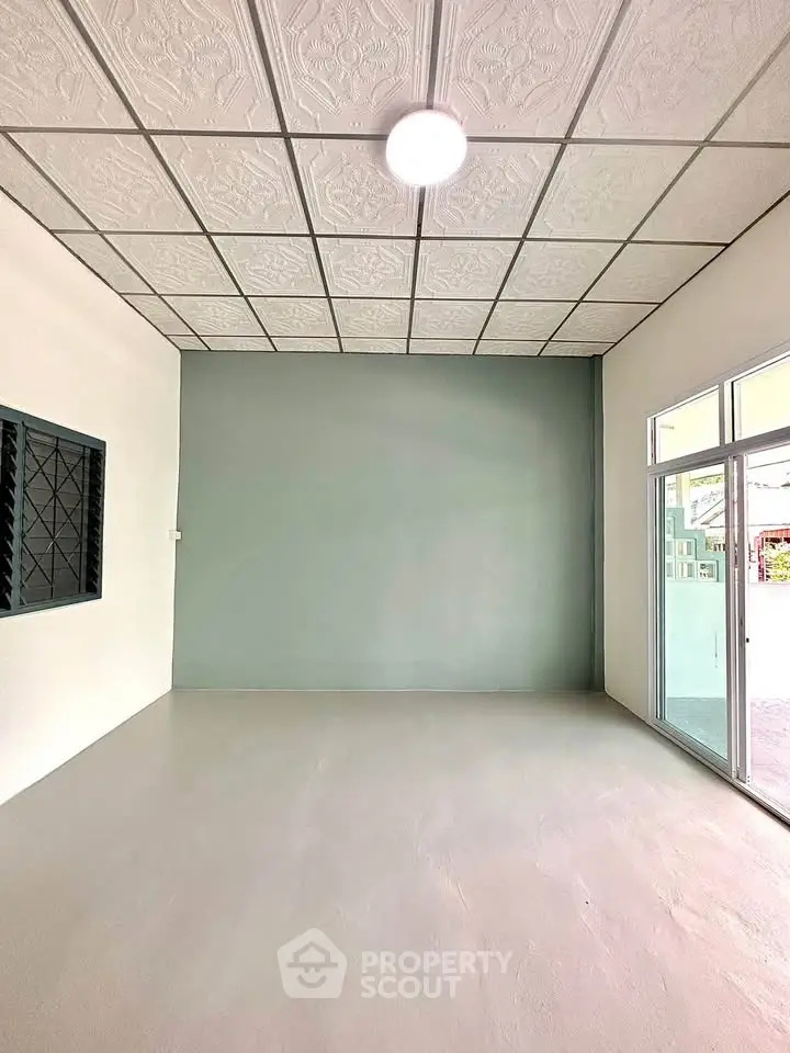 Spacious empty room with modern ceiling and large window, perfect for customization.