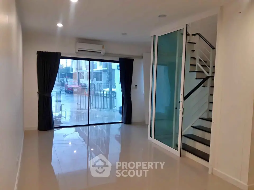 Modern living room with large glass doors and staircase, ideal for family gatherings.