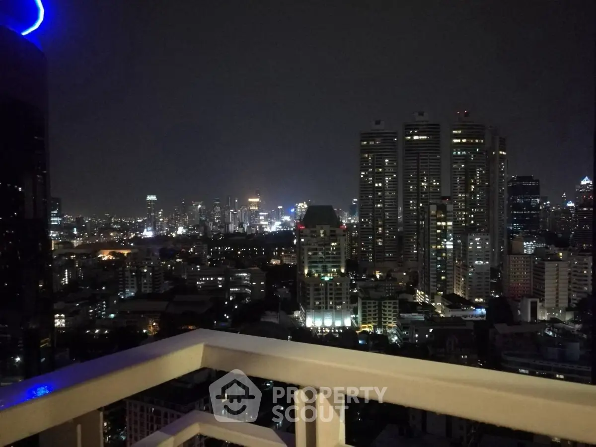 Stunning cityscape view from a high-rise balcony at night, showcasing vibrant urban lights.