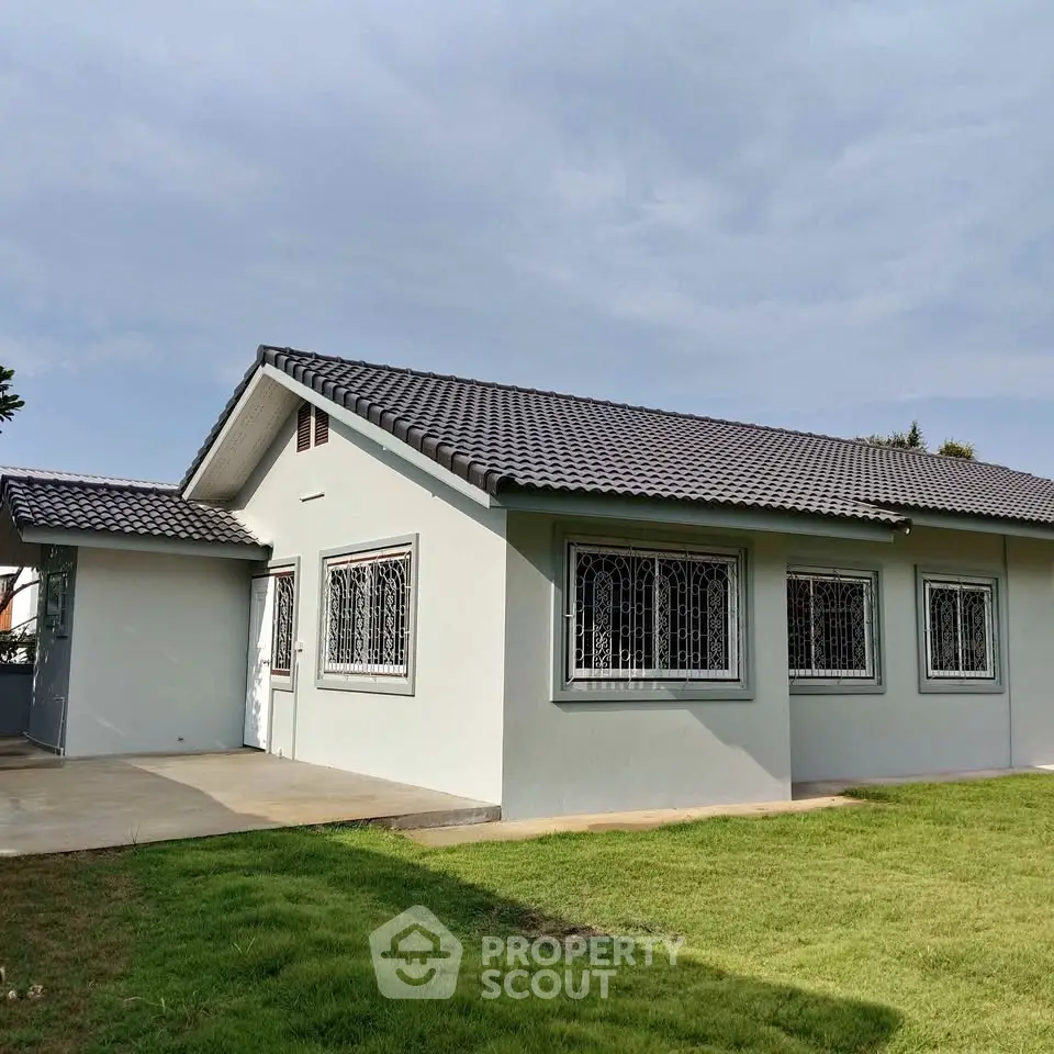 Charming single-story home with tiled roof and spacious green lawn, perfect for family living.