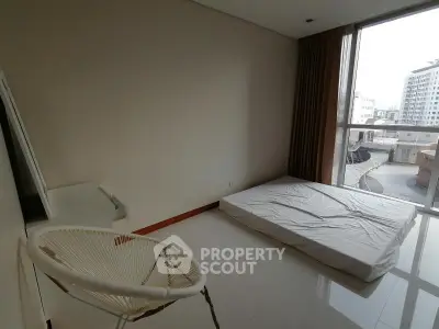 Spacious bedroom with large window and minimalist decor in modern apartment.
