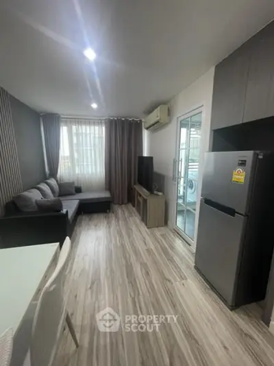 Modern living room with sleek design, featuring a cozy sofa, flat-screen TV, and stylish flooring.