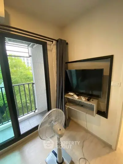 Modern apartment corner with balcony view, TV setup, and fan for comfort.