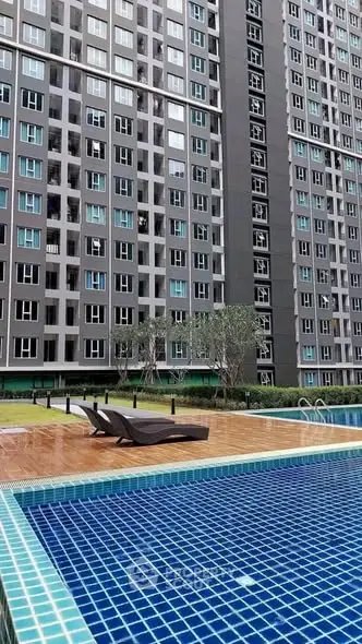 Modern high-rise building with luxurious poolside area and sun loungers.
