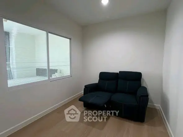 Cozy small room with a black recliner sofa and wooden flooring