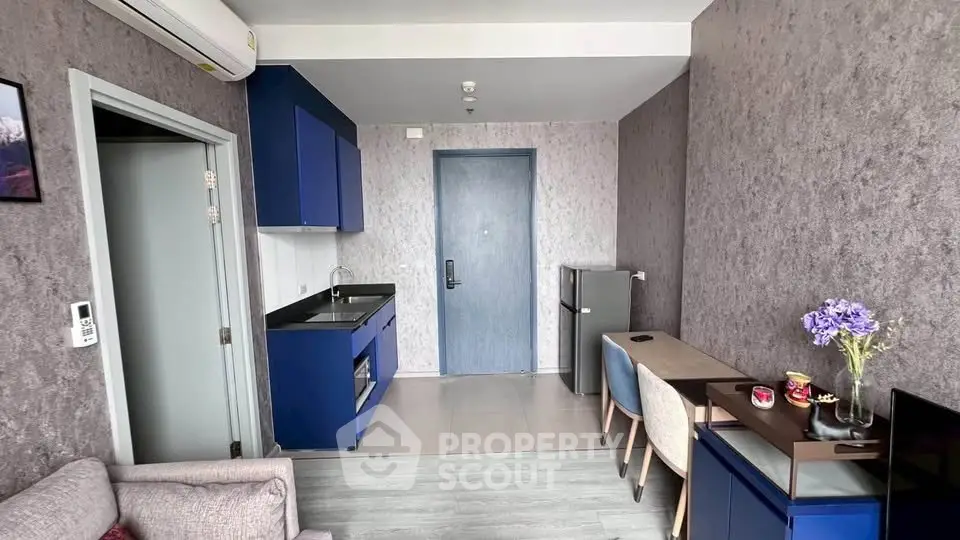 Modern living room with blue kitchen cabinets and cozy seating area, perfect for urban living.