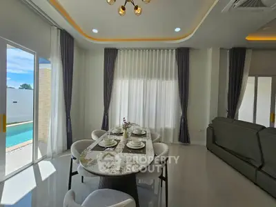 Elegant dining area with pool view, featuring modern decor and ample natural light.